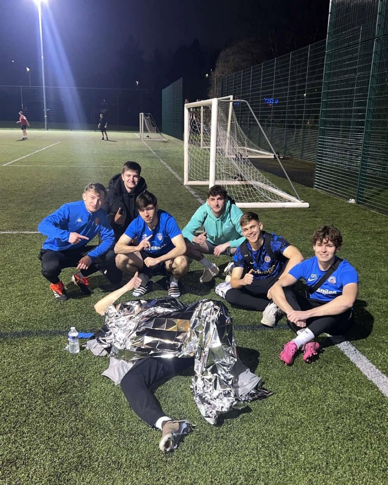 A football team recovering on the pitch after a night session